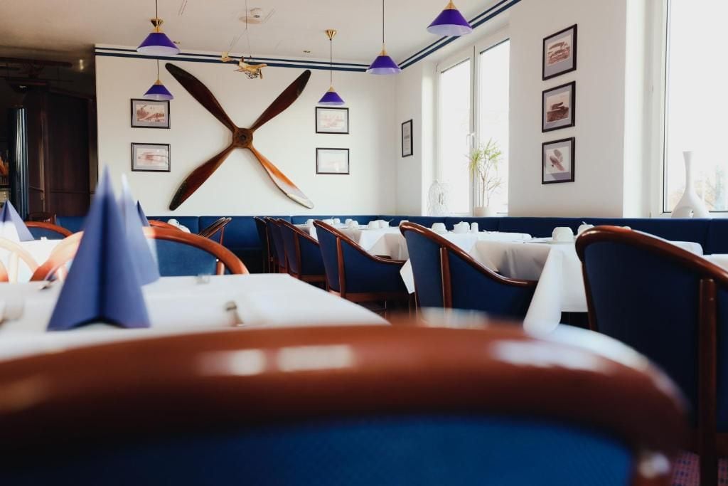 Un espace repas avec des banquettes recouvertes d’un tissu bleu, des nappes blanches et des luminaires suspendus.