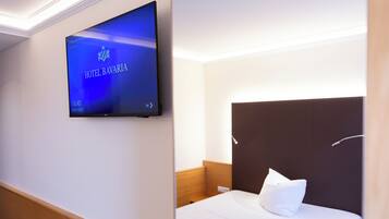 Ein Hotelzimmer mit einem an der Wand befestigten Flachbildfernseher, der den Namen und das Logo des Hotels zeigt.