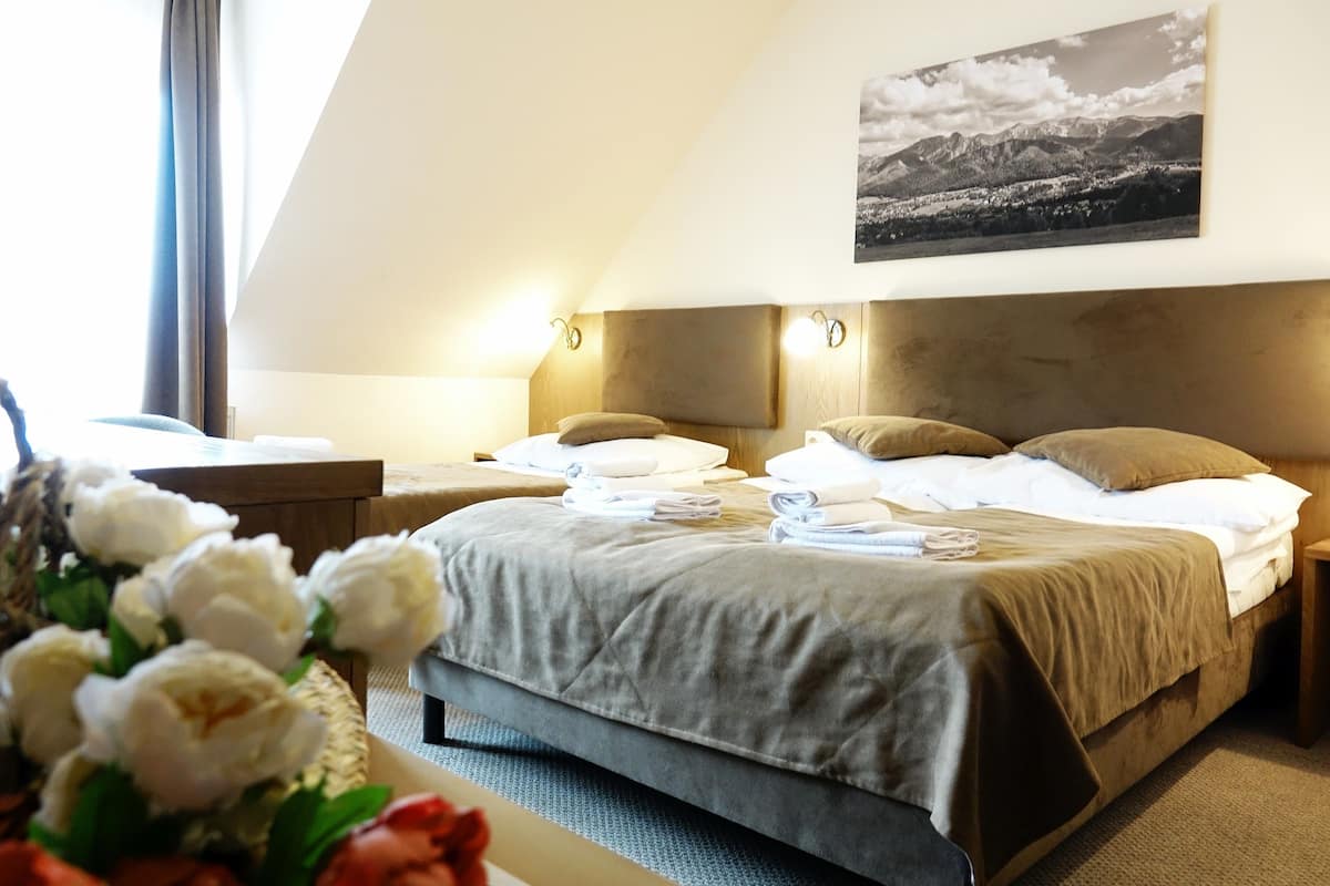 Habitación de hotel con cama, mesitas de noche, una imagen colgada en la pared y una ventana con cortinas.
