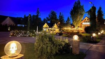 A log cabin-style building with a sign indicating a restaurant, surrounded by trees and a well-lit garden.