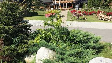 Un chalet doté d’un grand bâtiment en bois, d’un espace extérieur aménagé pour s’asseoir et d’un jardin bien entretenu avec des rochers et des arbustes.