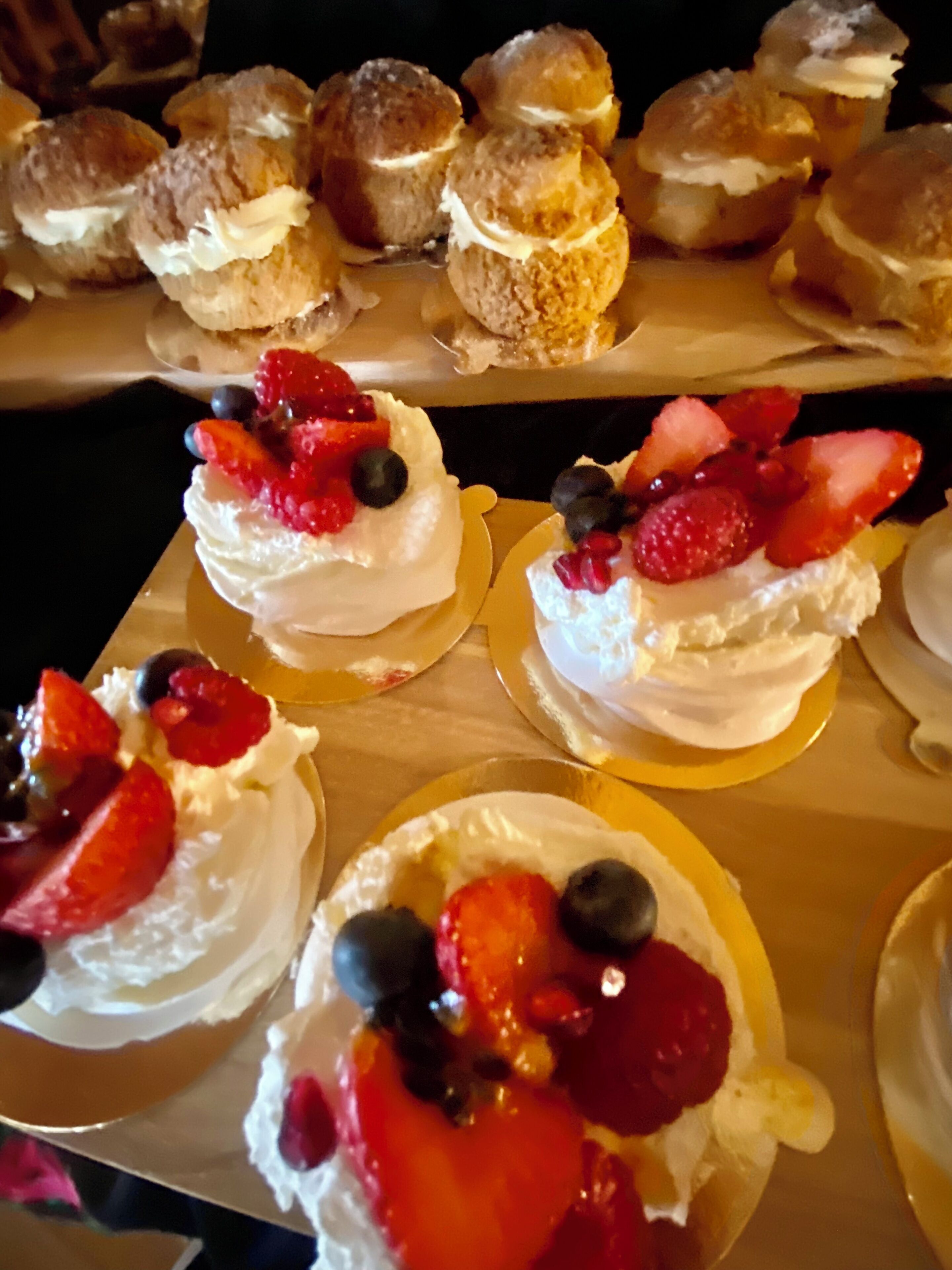 Una bandeja de postres con pasteles cubiertos de merengue y adornados con fresas y arándanos.