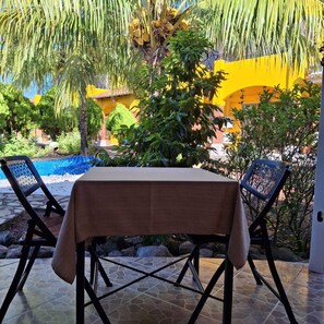 Relax in a tranquil outdoor space surrounded by lush tropical plants and a serene pool.