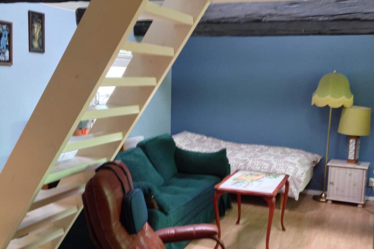 Une pièce avec un canapé vert, un fauteuil en cuir marron, une petite table et une lampe.