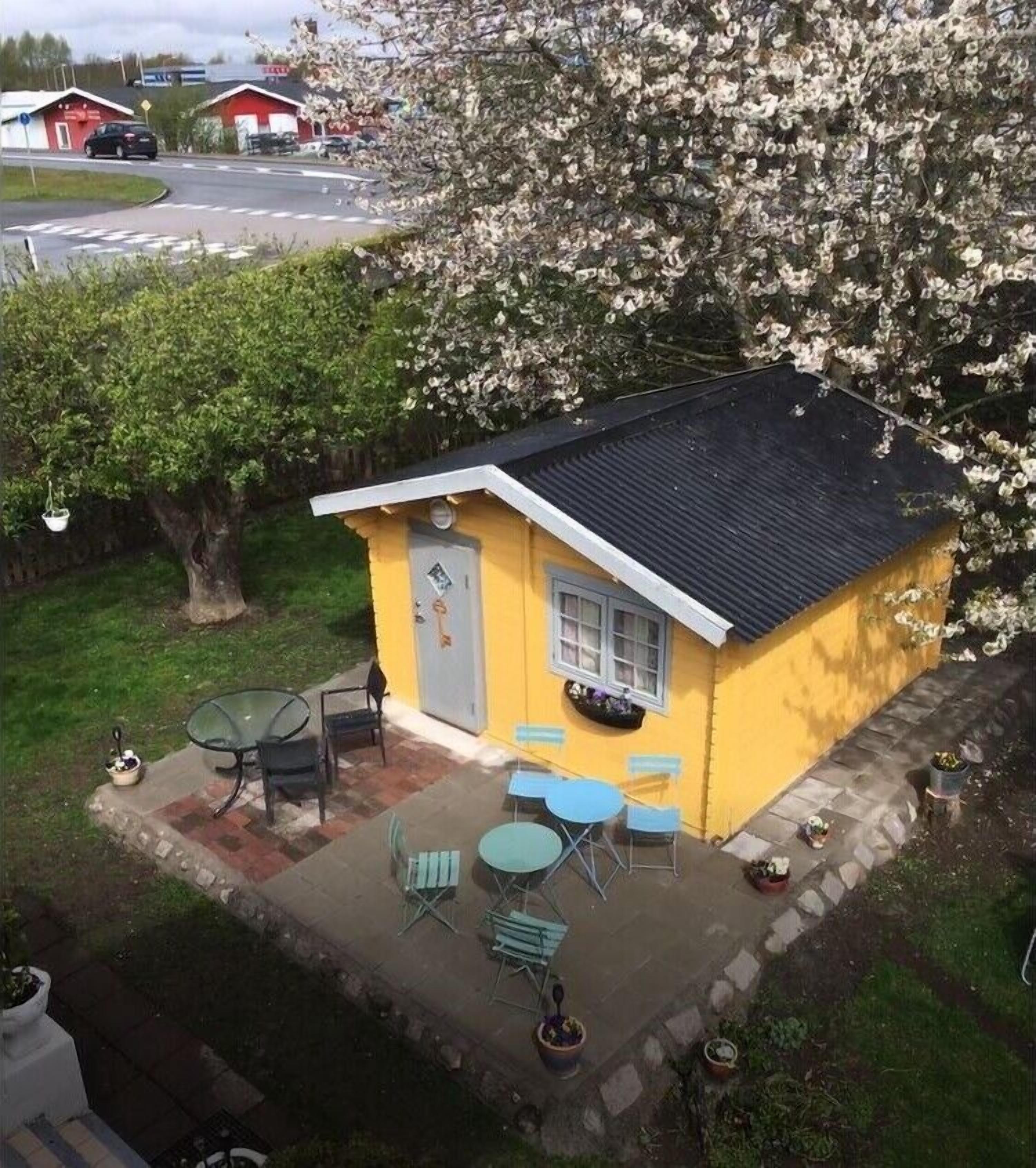Un pequeño edificio amarillo con un patio, una mesa y sillas.