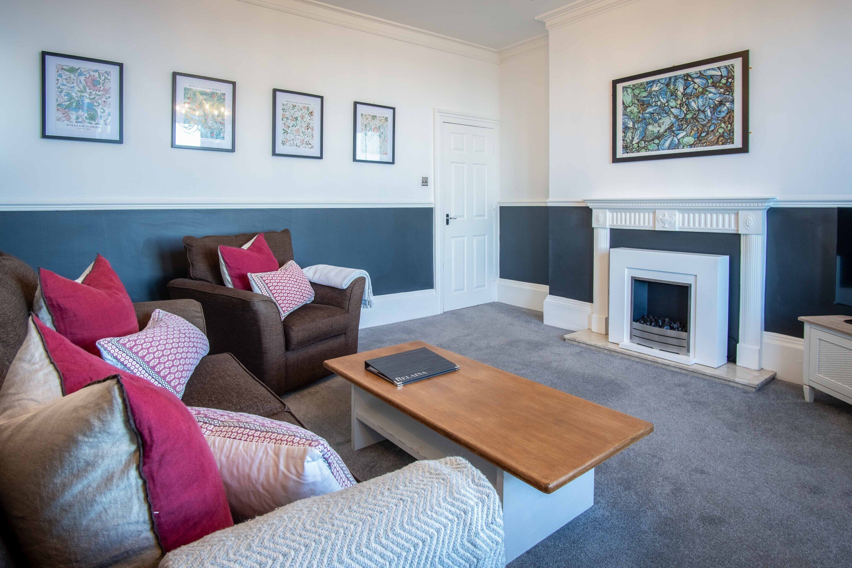 A living room with a brown sofa, a wooden coffee table, and a white fireplace.