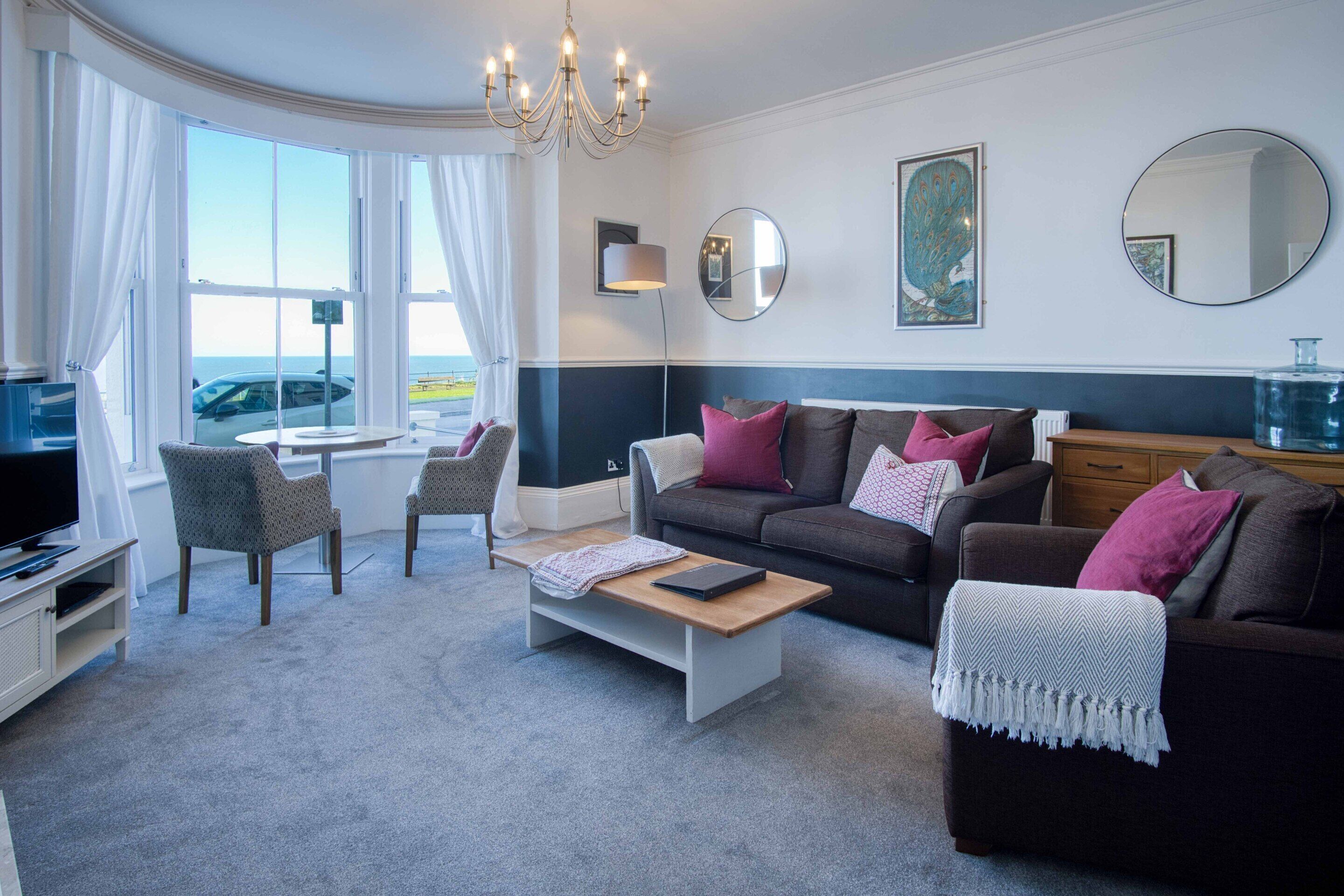 A modern living room with a sofa, armchairs, a coffee table, and a TV.