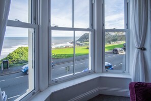 A room with a large window overlooking a coastal road and cliffs. - Blue Horizon Apartments at The Helaina (Scarborough)