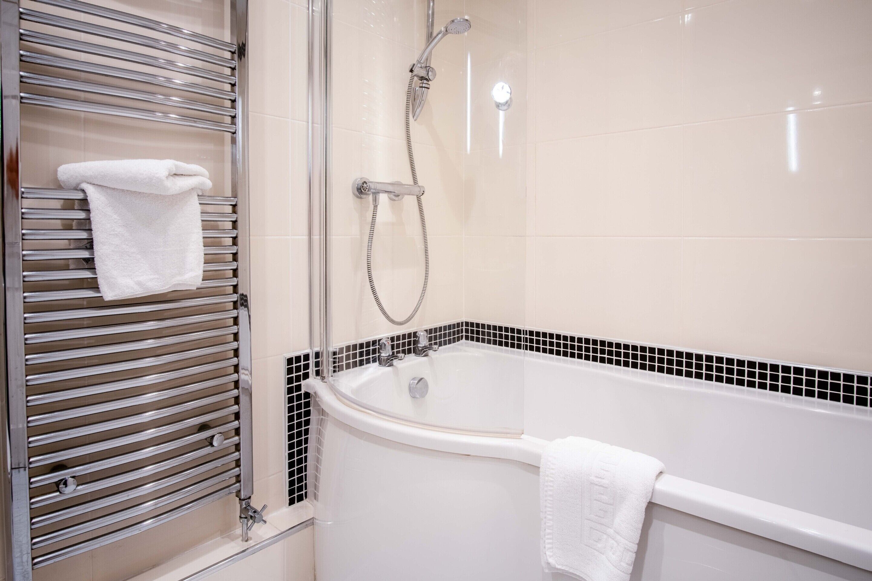 Une salle de bain moderne équipée d’une baignoire, d’une douche et d’un porte-serviettes.