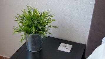 Una planta en test amb una taula negra al costat d'una paret blanca amb una presa elèctrica.