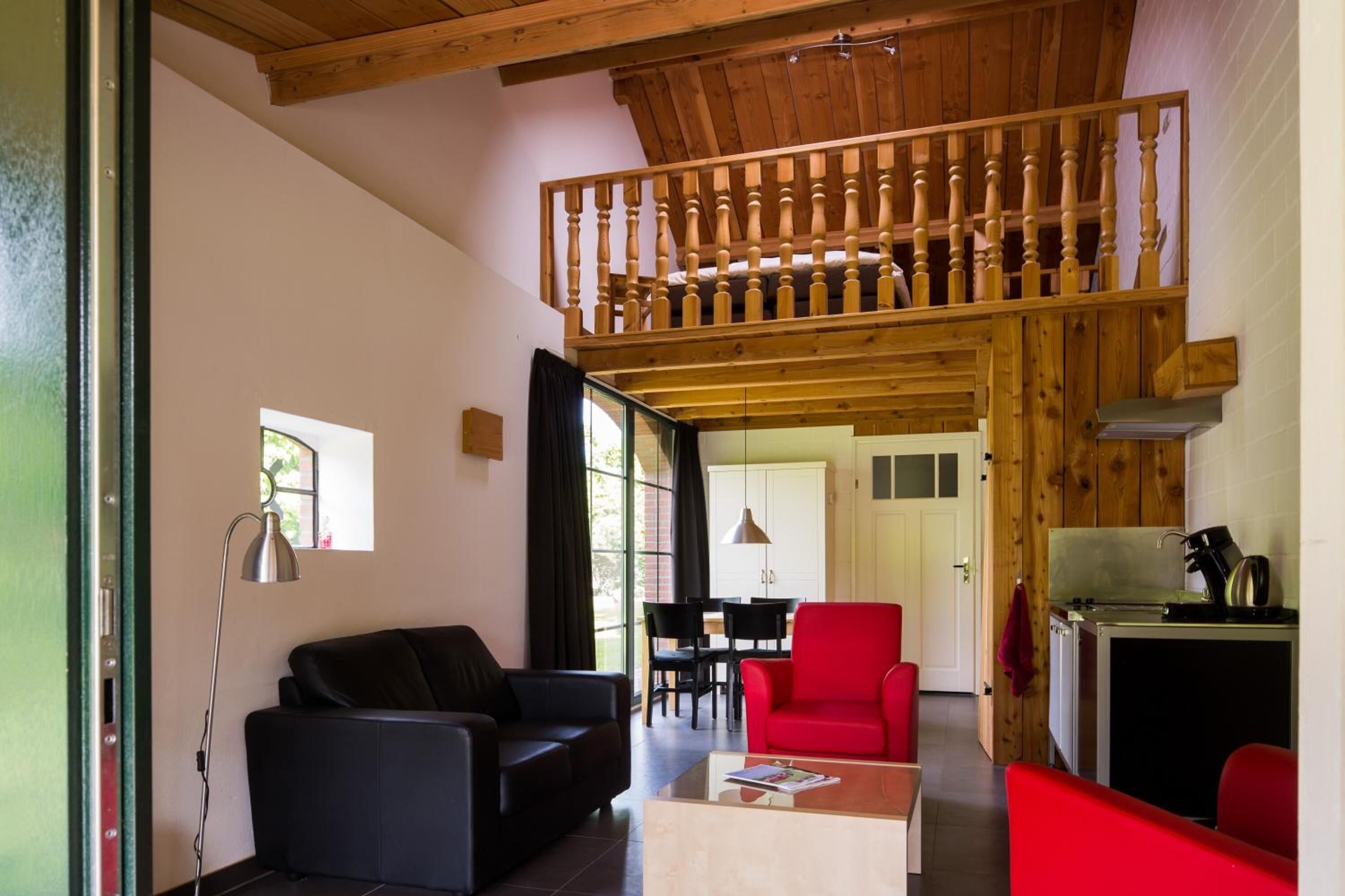 A spacious living area with a high ceiling, a dining area, and a kitchen.