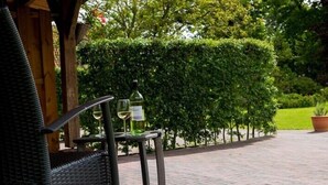 Un área de estar al aire libre con una mesa, sillas, una botella de vino blanco y una copa.