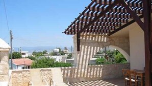 Un balcón con una pérgola, muros de piedra y vista panorámica de la ciudad.