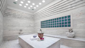 A modern bathroom with a marble vanity, a large decorative tile wall, and a built-in bathtub.
