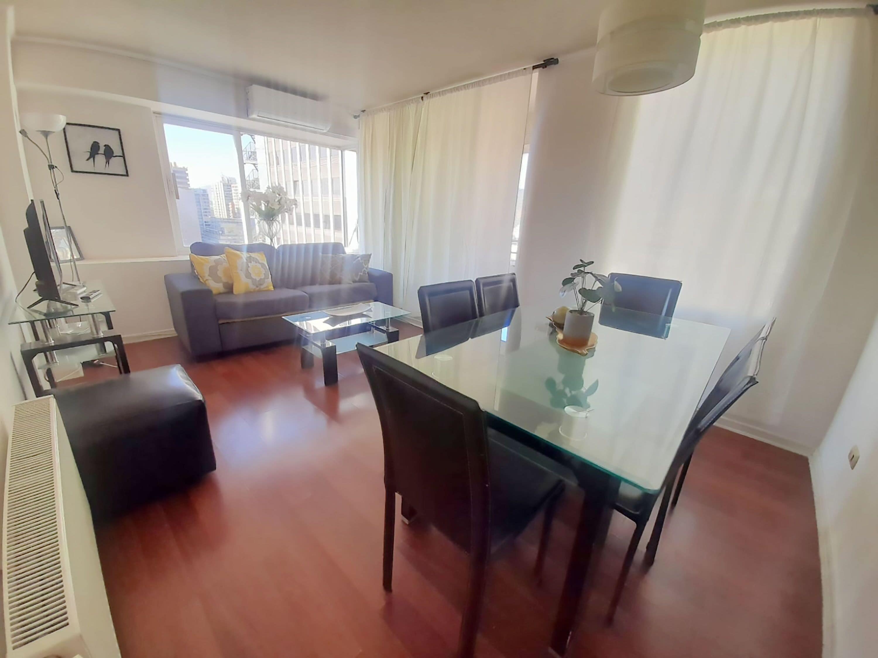 A modern living room with a glass dining table, a sofa, and a coffee table.