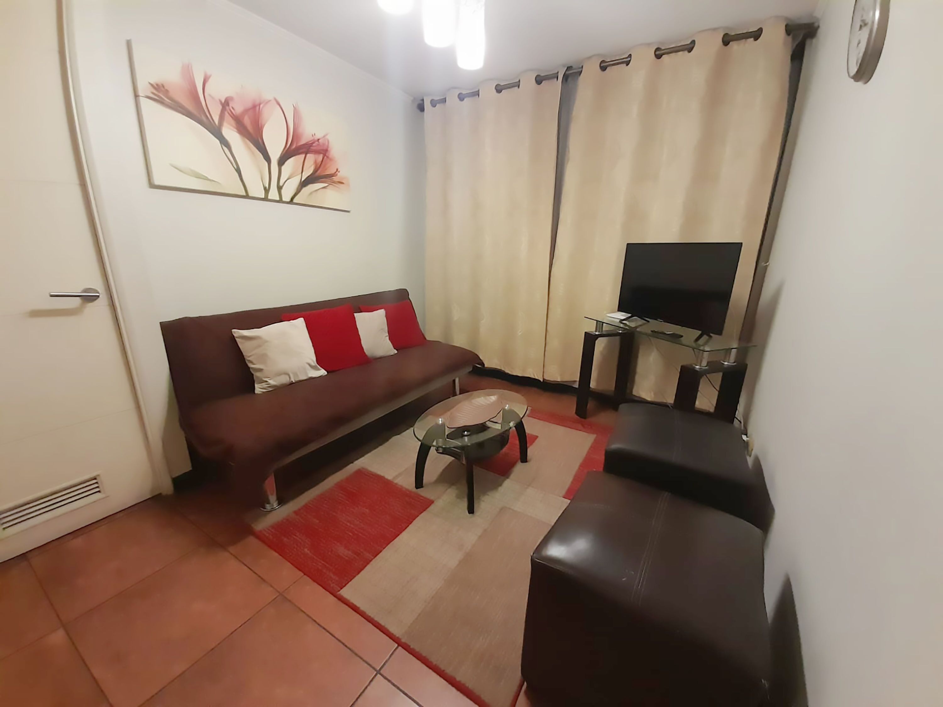 A living room with a sofa, a coffee table, a TV on a stand, and a painting on the wall.