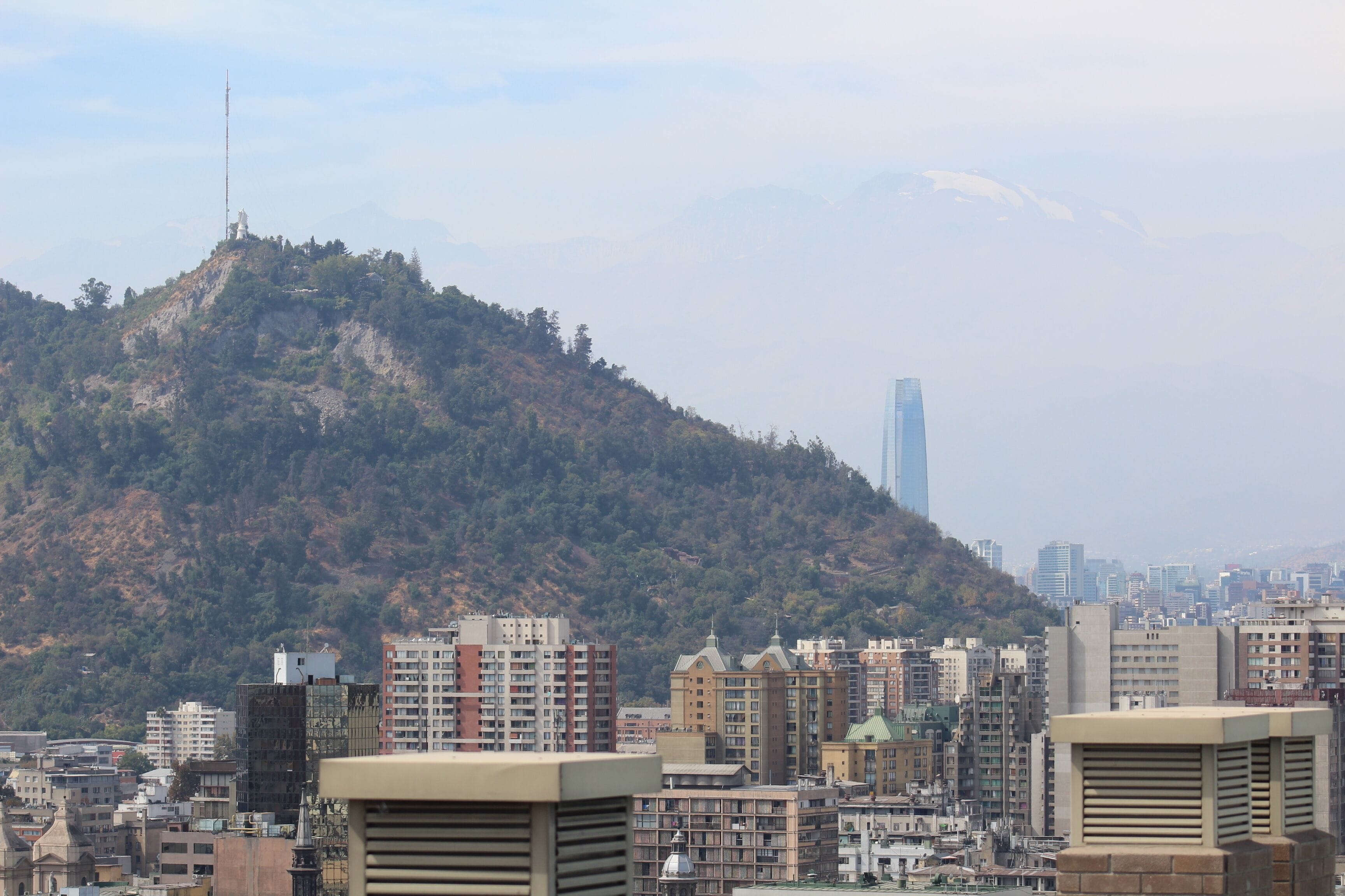 A cityscape with a prominent hill, buildings, and a tall skyscraper in the background.