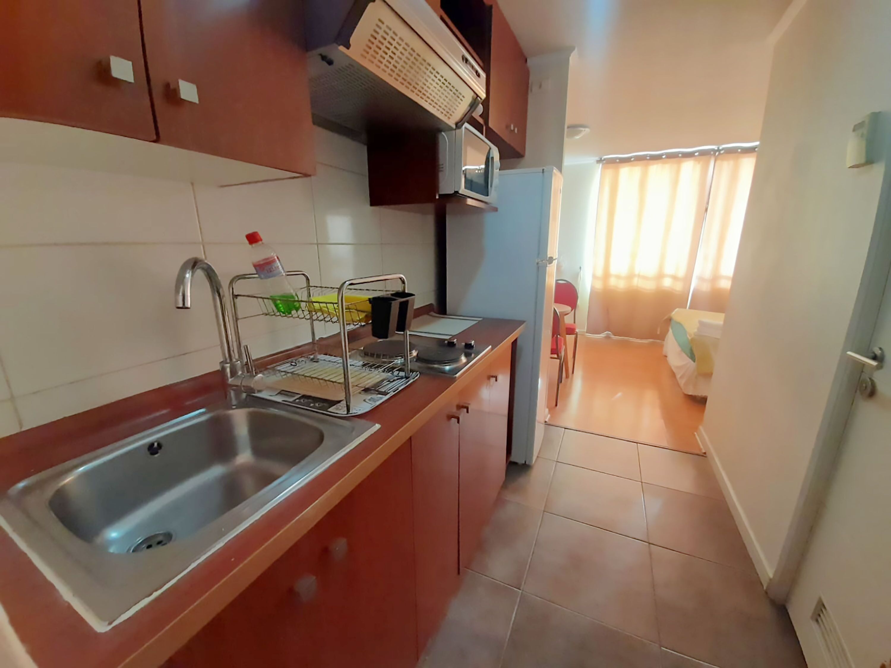 A compact kitchen with a sink, a microwave, and a small dining area with a chair and table.