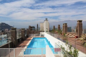 A rooftop pool with a city view, surrounded by glass railings and potted plants. - VIP Apartments Chile (Santiago)