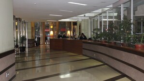 Un hall d’entrée spacieux, doté d’un comptoir de réception, de plantes en pot et d’un sol carrelé.