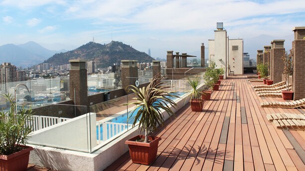 Terraza en la azotea con piscina, plantas en macetas y vistas de la ciudad.