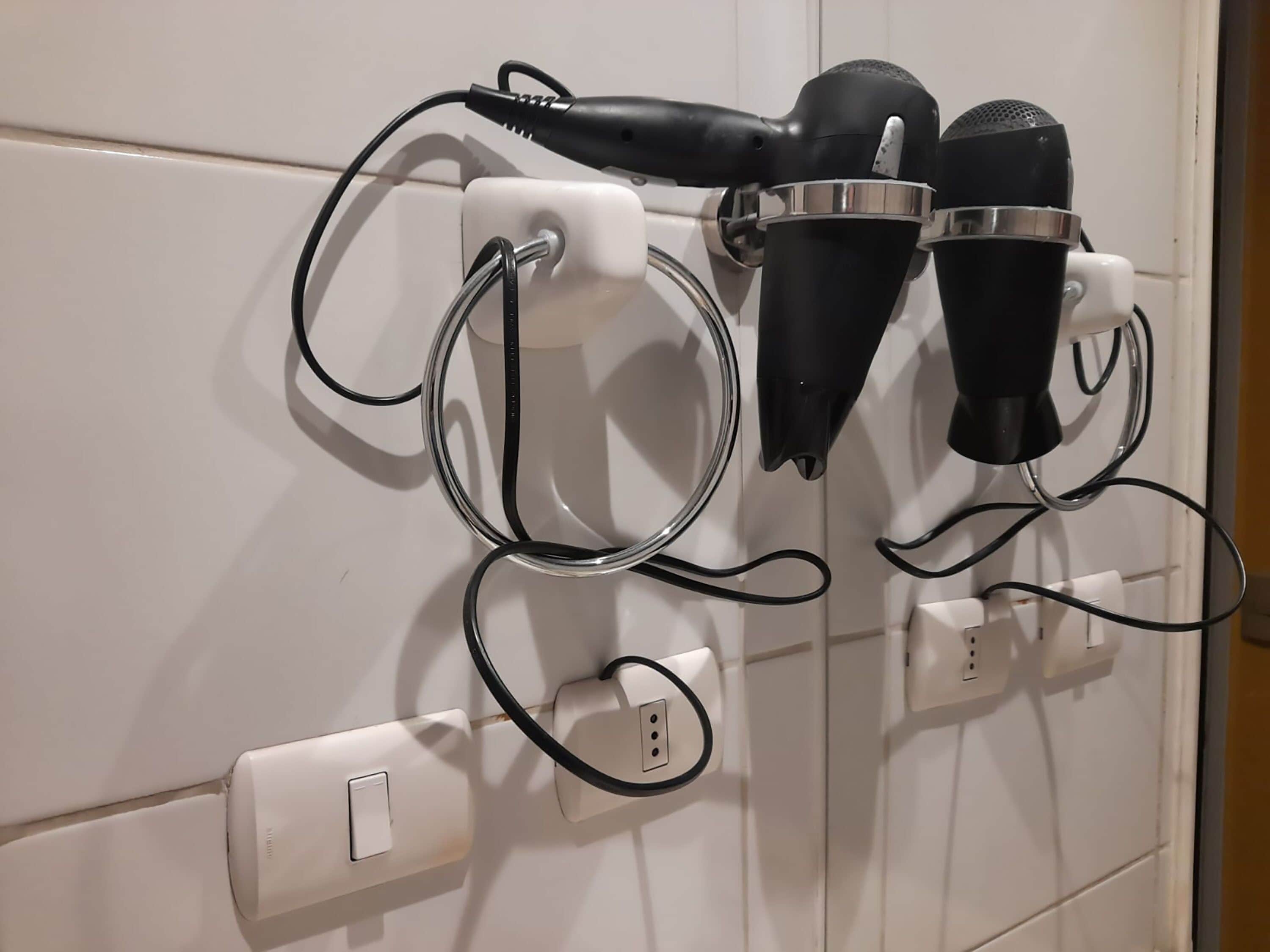 Una presa elettrica a muro con ciabatta e due asciugacapelli collegati.