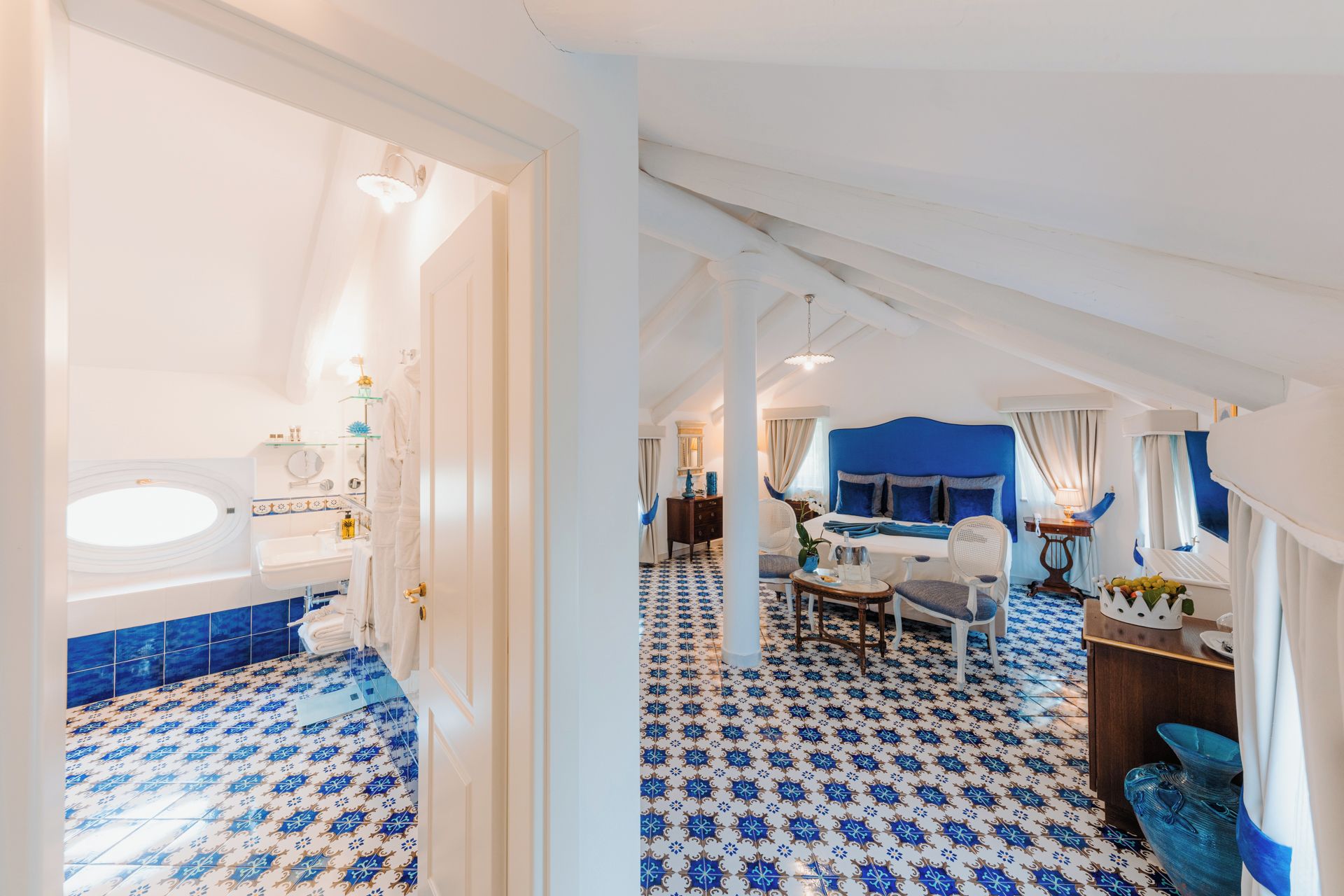 A hotel room with a bathroom, a dining area, and a bedroom.