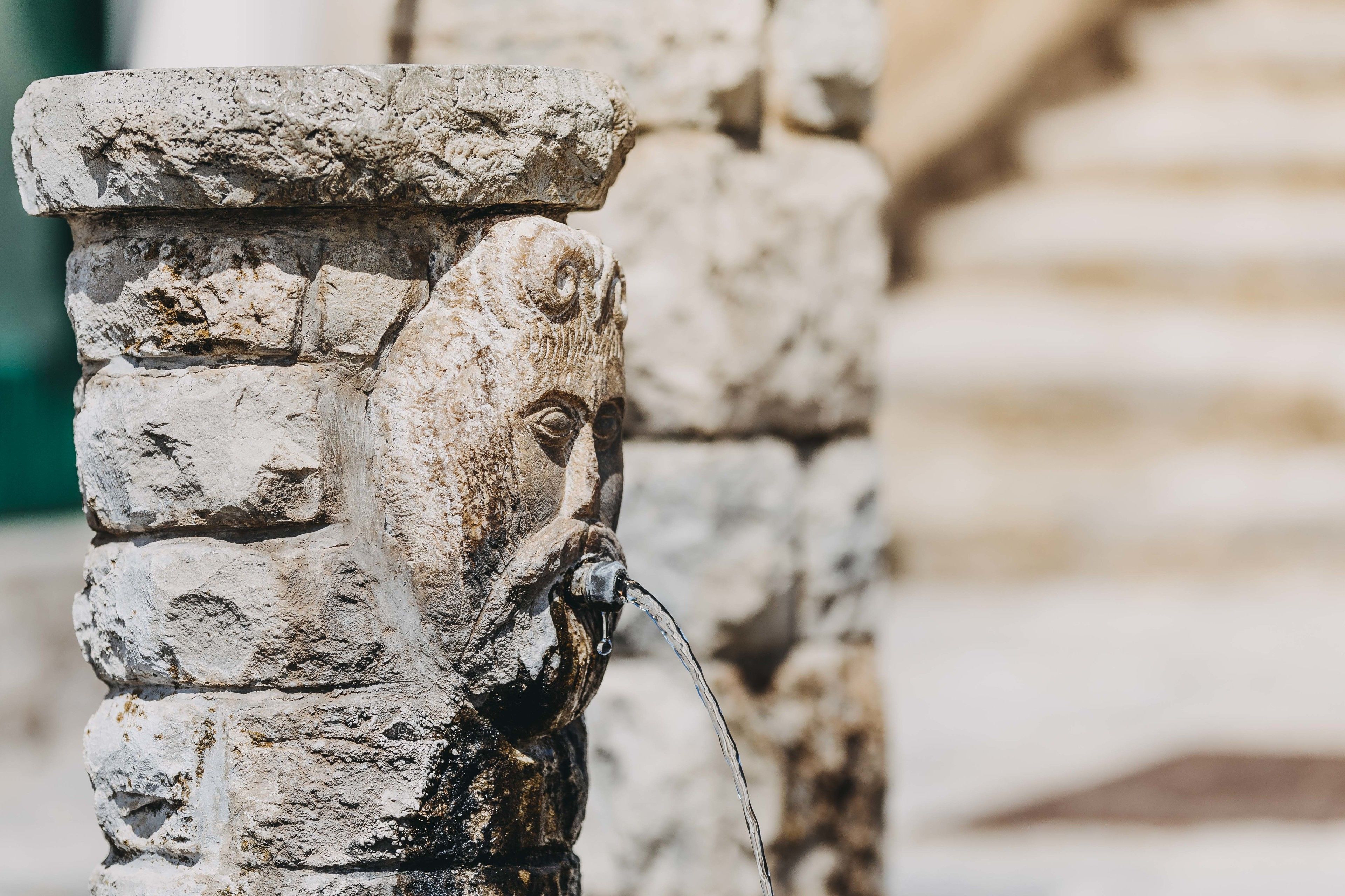 A stone pillar with a carved face and a water spout.