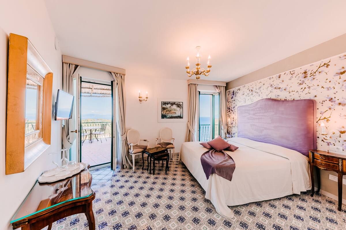 Une chambre d’hôtel équipée d’un lit, d’un bureau, d’une chaise, d’une table et offrant une vue sur l’extérieur.