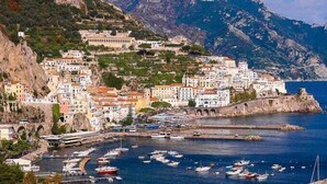 A coastal town with buildings on a hillside, a marina with boats, and a mountain backdrop. - Palazzo Pascal - Amalfi Coast Luxury Experience (Scala)