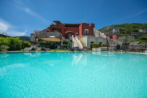 A swimming pool with lounge chairs and a red building in the background. - Palazzo Pascal - Amalfi Coast Luxury Experience (Scala)