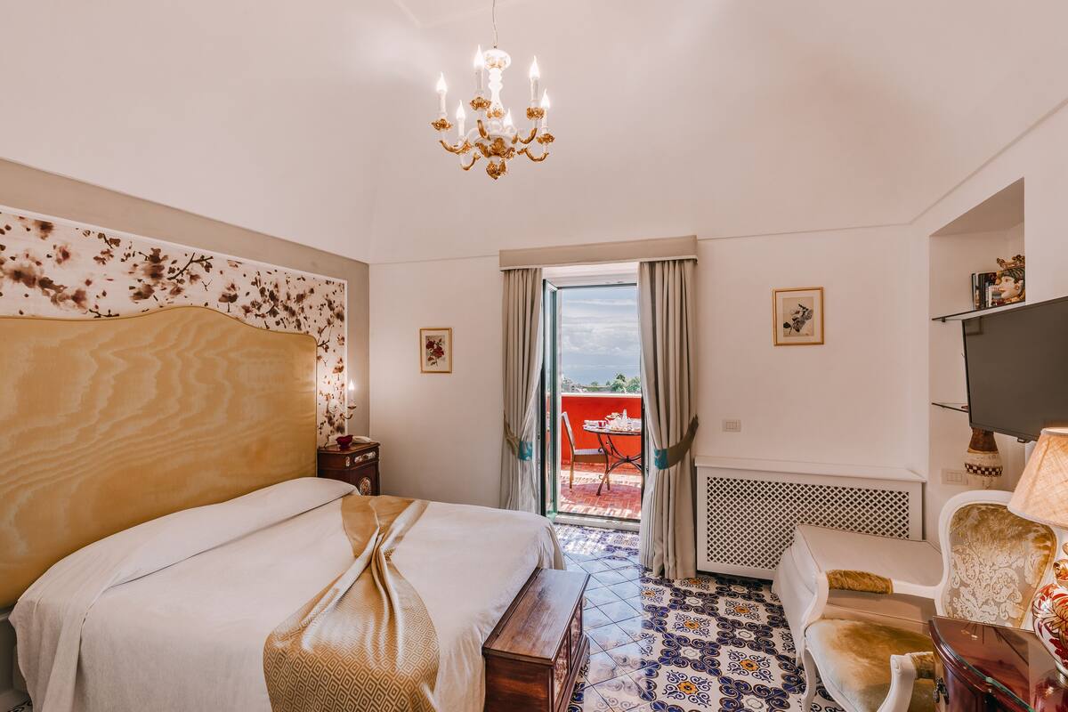 Une chambre d’hôtel avec un grand lit, un lustre, une télévision et une vue sur l’extérieur.