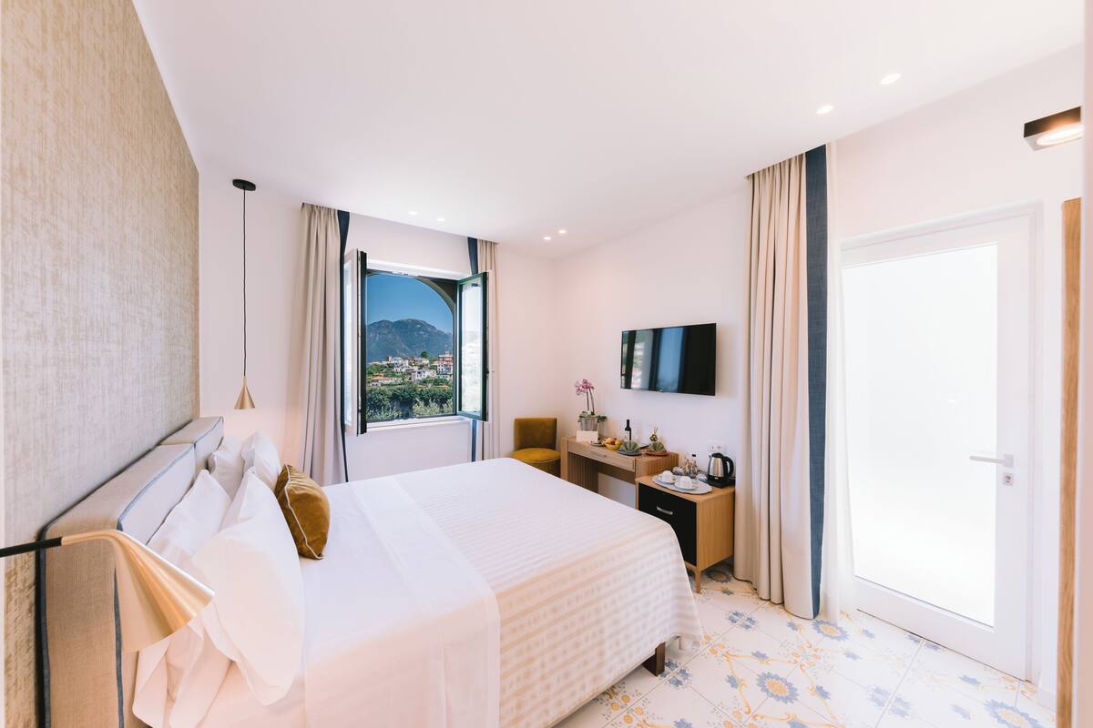 Une chambre d’hôtel avec un lit, un bureau, une télévision et une vue sur les montagnes.