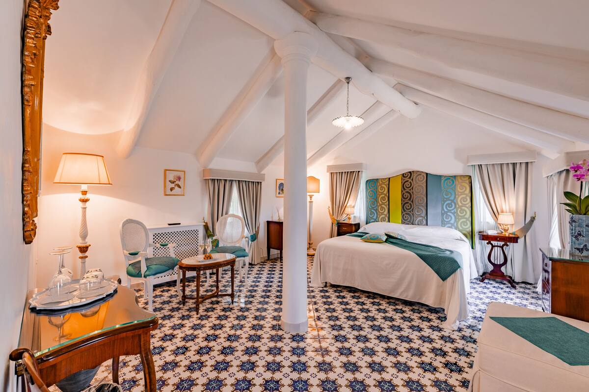 Une chambre d’hôtel avec un grand lit, un coin salon comprenant une chaise et une table, et un miroir décoratif.