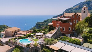 A coastal resort with a swimming pool, outdoor seating, and a view of the sea. - Palazzo Pascal - Amalfi Coast Luxury Experience (Scala)
