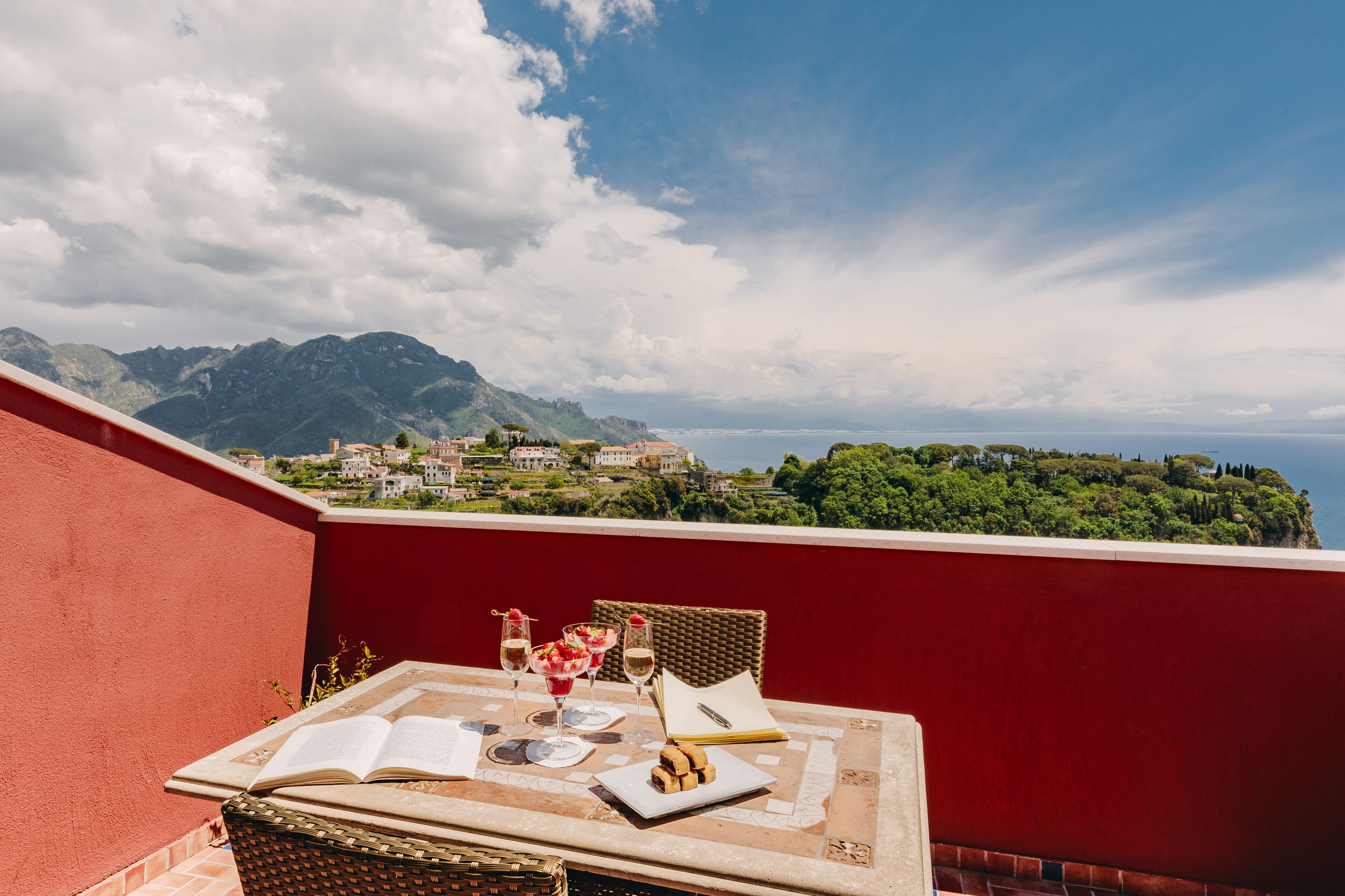 A terrace with a table set for two, overlooking a scenic mountain view.