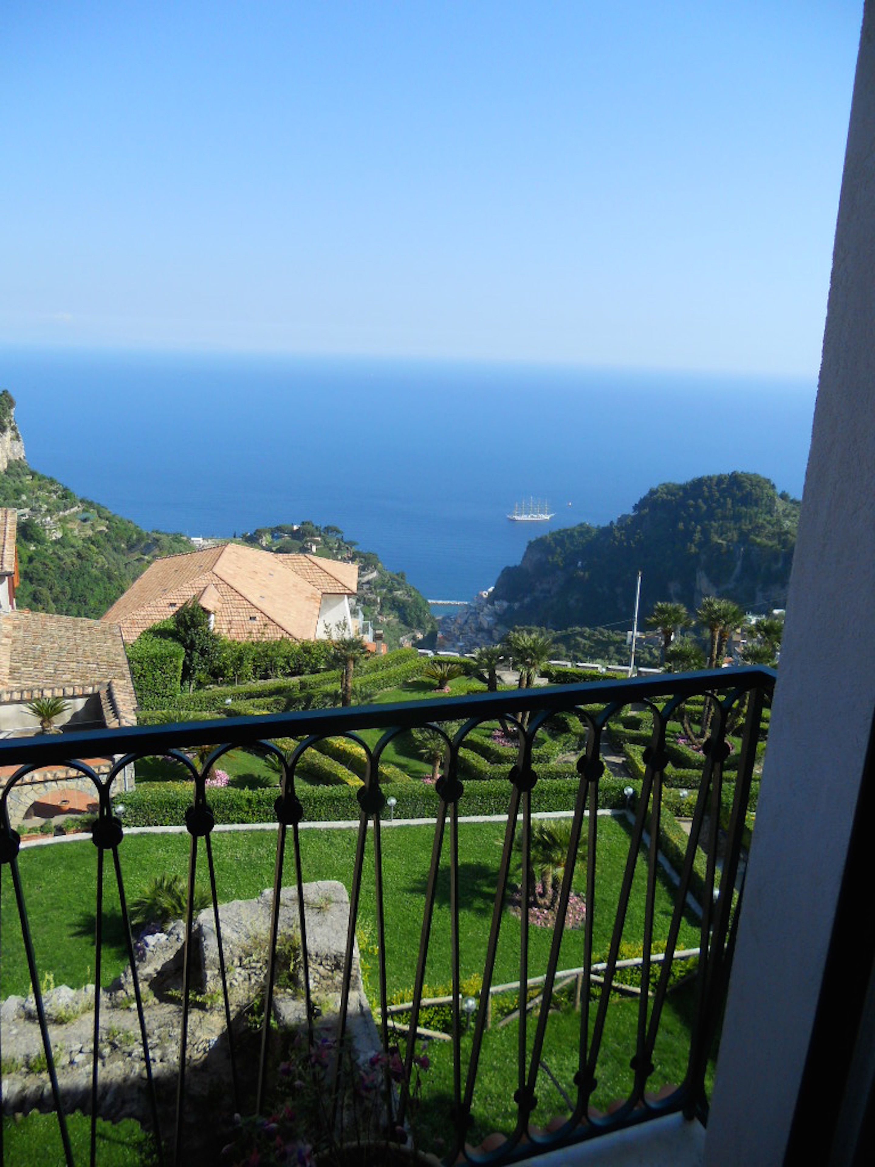 Un balcon avec vue sur la mer, la verdure et les bâtiments.