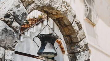 A rustic stone archway with a metal bell hanging from it.