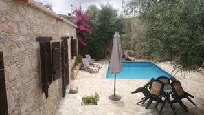 A stone building with a pool, outdoor seating, and potted plants. - Kirithra (Neo Chorio)