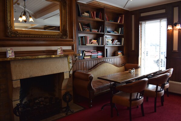 A library with a fireplace, bookshelves, a wooden table, and chairs.