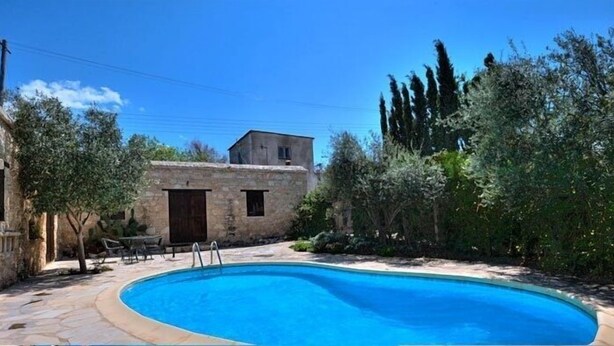 A swimming pool surrounded by stone buildings and greenery. - Kipseli (Neo Chorio)