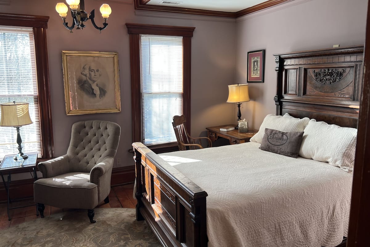 Une chambre à coucher avec un grand lit, une chaise, un bureau et un lustre.