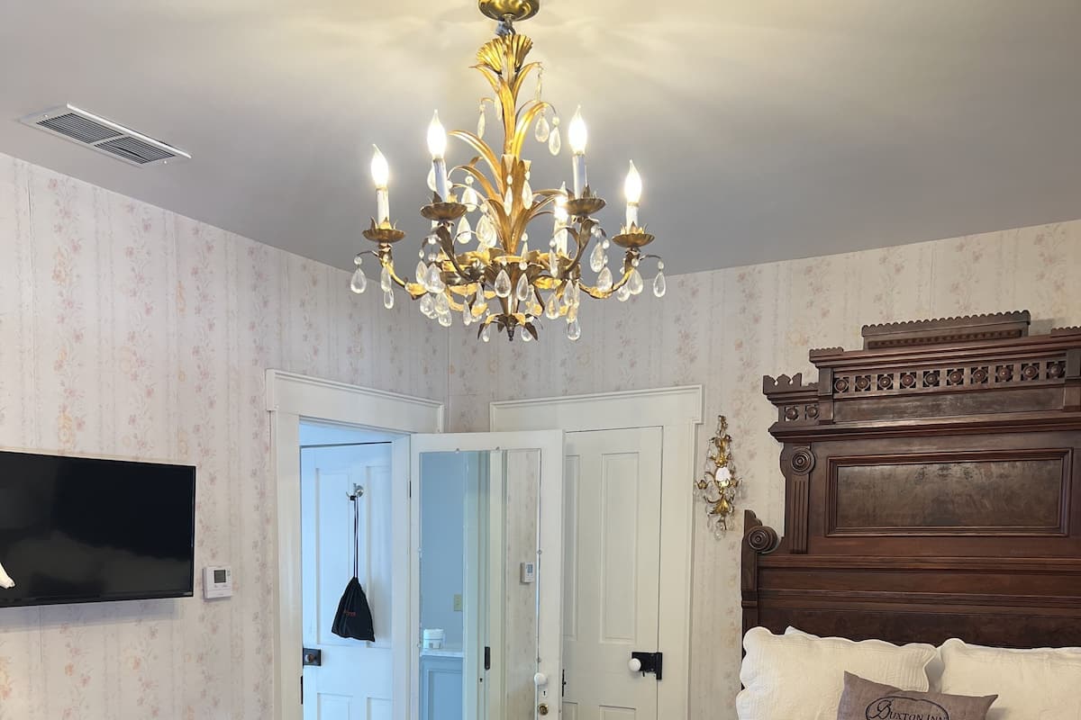 Une chambre à coucher avec un lit en bois, un lustre, une télévision et un bureau.