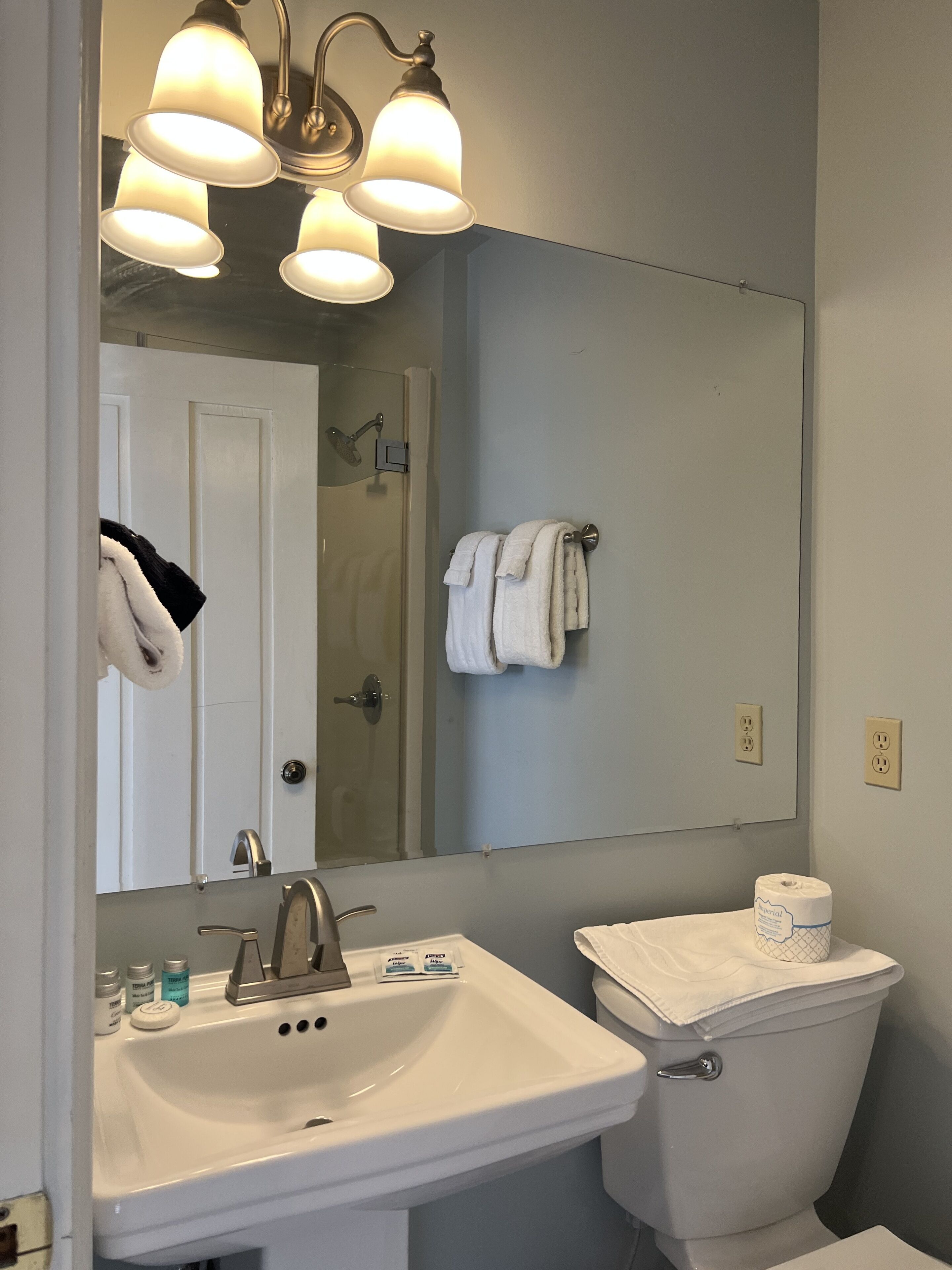 A bathroom with a white sink, a toilet, and a mirror. There are two towels hanging on the wall.