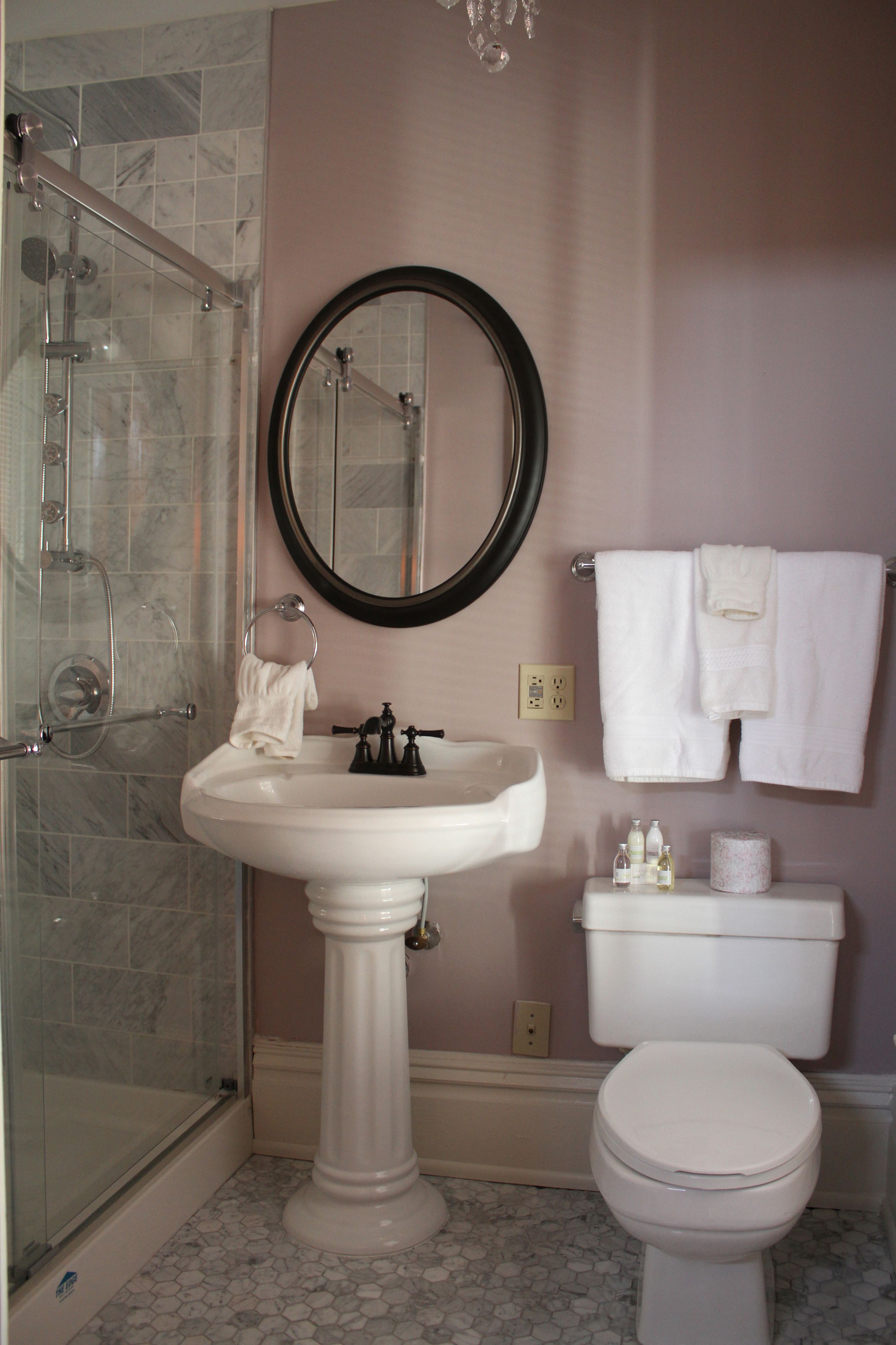 A bathroom with a pedestal sink, toilet, and a glass-enclosed shower.