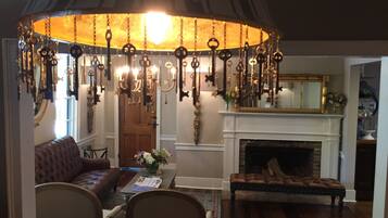 A room with a fireplace, a sofa, a dining table, and a chandelier with hanging keys.