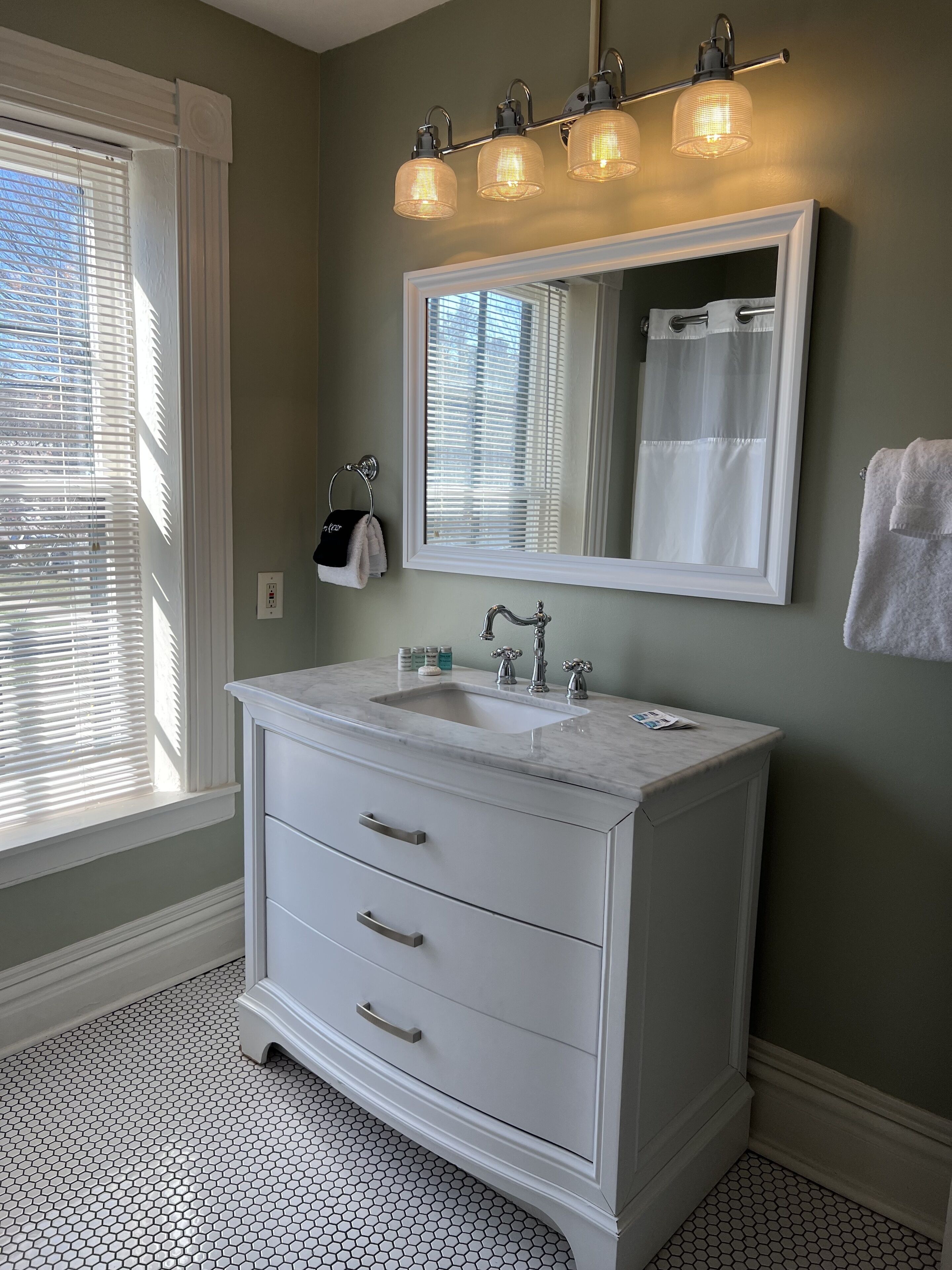 A bathroom with a white vanity, a large mirror, and three wall-mounted lights.