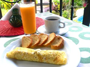 A breakfast setting with toast, an omelette, a glass of orange juice, and a cup of coffee on a table with a green and white patterned tablecloth. - Bubinzana Magical Lodge (Tarapoto)