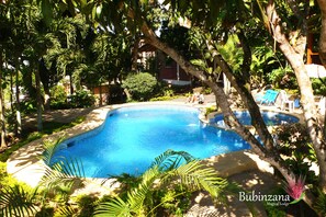 A pool surrounded by lush greenery and a building in the background. - Bubinzana Magical Lodge (Tarapoto)