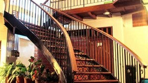 A spiral staircase with a wrought iron railing, leading to an upper floor.